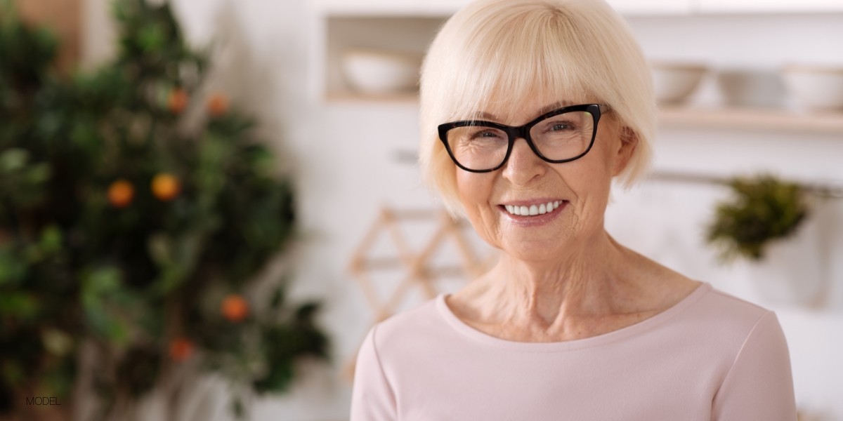 Older female with black rimmed glasses and beautiful full mouth of teeth